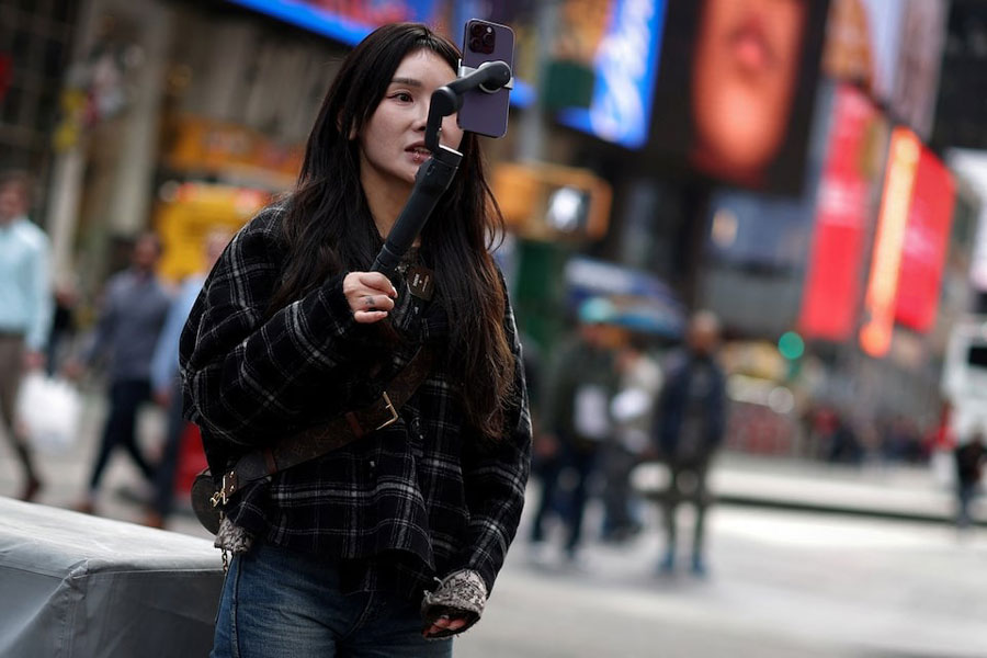 A woman makes a video to post on TikTok, Times Square, New York City, March 13, 2024.