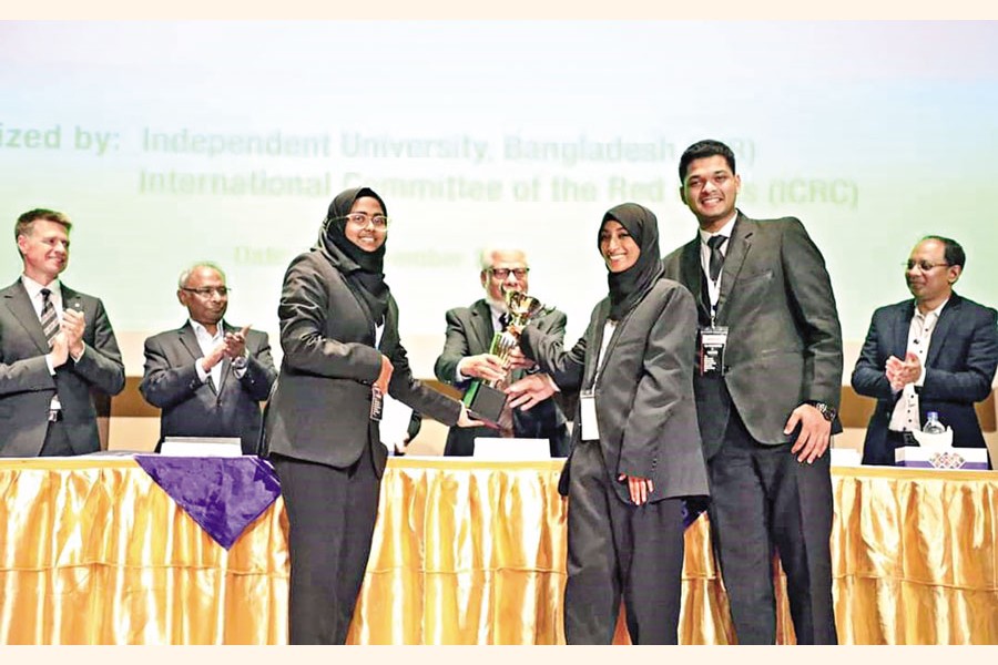 Team DU celebrates their championship victory at the 15th Henry Dunant Memorial Moot Court Competition 2024 held in Dhaka recently, with (from left) Jarin Anjum Tasnim, Anika Tahsina, and Rezoan Asraf proudly holding the trophy