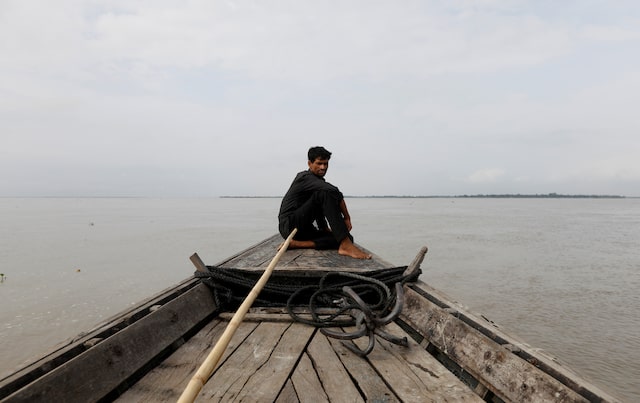 A man sits in a boat on the waters of the Brahmaputra river near the international border between India and Bangladesh in Dhubri district, in the northeastern state of Assam, India August 4, 2018. REUTERS/Adnan Abidi/File Photo