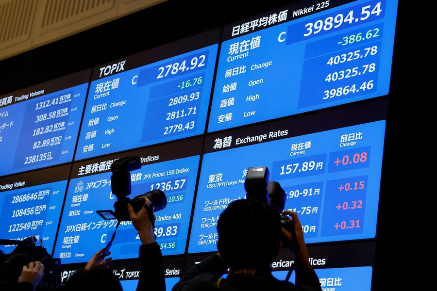 Photographers take photos of the stock closing price and forex exchange rates on a board during a ceremony marking the end of trading in 2024 at the Tokyo Stock Exchange (TSE) in Tokyo, Japan December 30, 2024.
