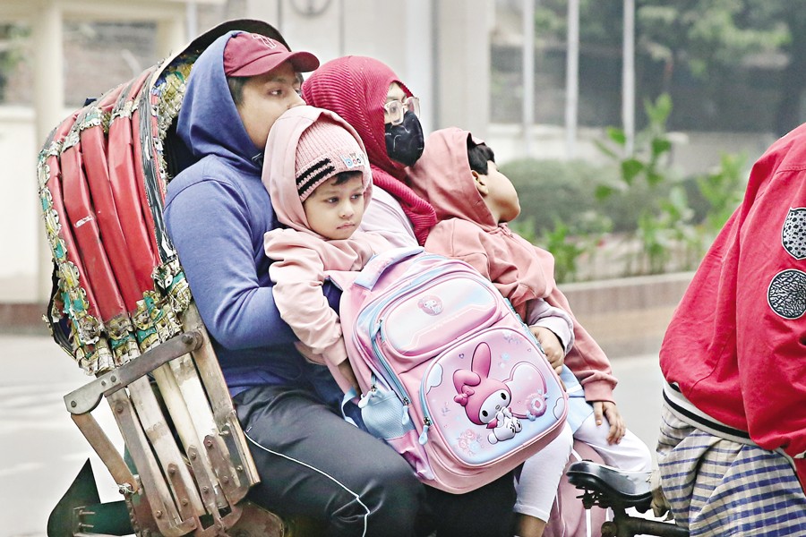 The country shivers with cold as mercury has dipped in its most parts with blankets of dense fog shrouding Dhaka city and elsewhere, and making the people feel the wind's icy blasts. The snap shows two guardians taking home their kids from school by rickshaw amid winter chill at Shantinagar neighbourhood on Thursday morning. — FE Photo by Asad-Uz-Zaman