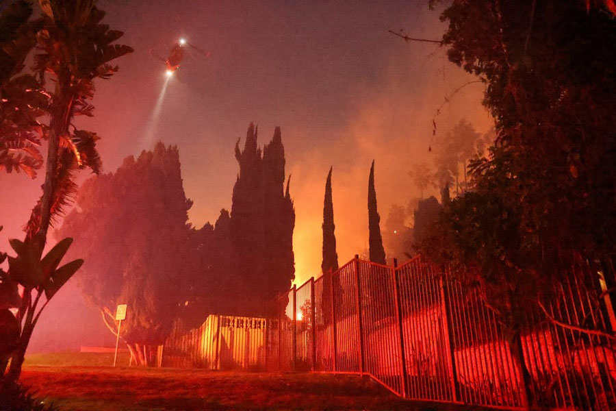 A helicopter flies as smoke rises from the Sunset Fire in the hills overlooking the Hollywood neighborhood of Los Angeles.
