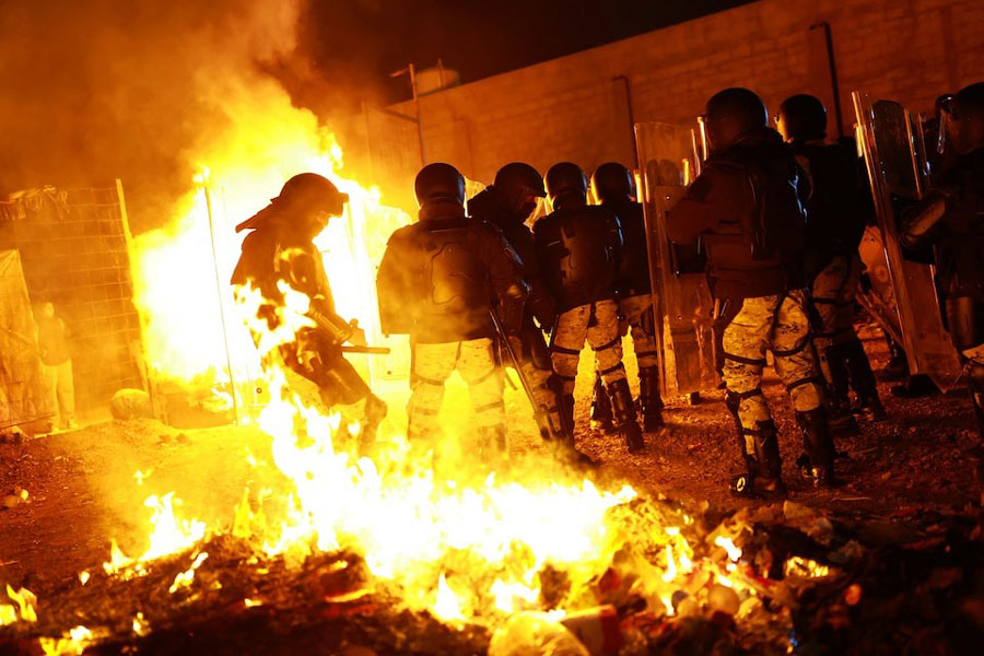 Members of the Mexican National Guard in riot gear take part in an operation to remove migrants from a camp, as migrants burn their belongings, in Chihuahua, Chihuahua state, Mexico January 18, 2025.