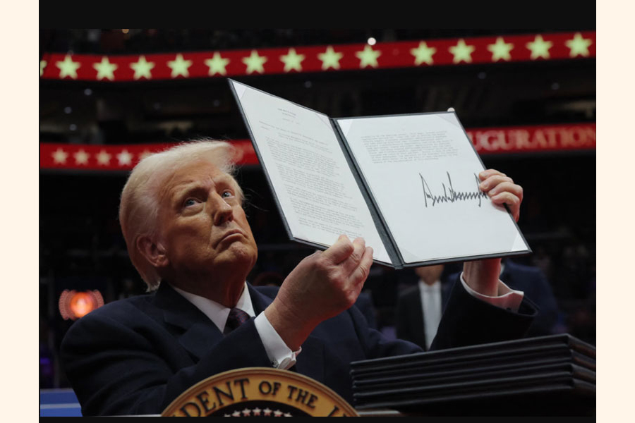 President Donald Trump holds up executive orders after signing it at an indoor Presidential Inauguration parade event in Washington, Monday, Jan. 20, 2025