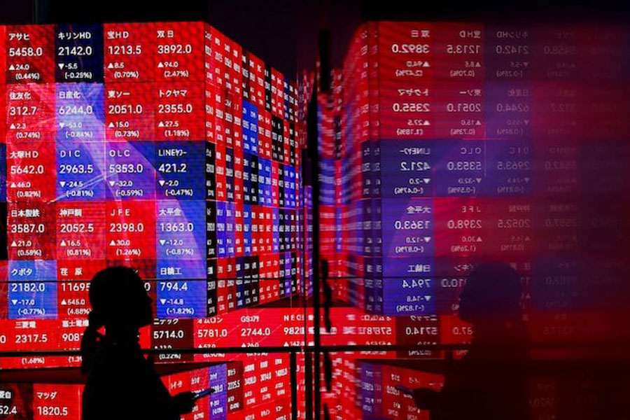 A visitor stands next to an electronic screen displaying Japan's Nikkei stock prices quotation board, inside a building in Tokyo, Japan February 22, 2024.