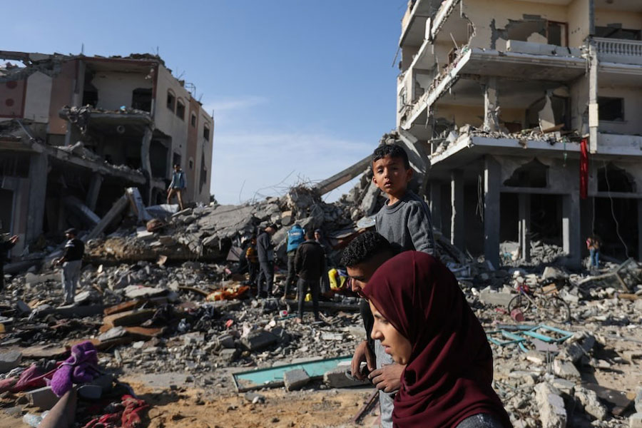 Displaced Palestinians return to their homes as they walk near houses destroyed in an Israeli strike during the conflict, amid the temporary truce between Hamas and Israel, in Khan Younis in the southern Gaza Strip November 24, 2023.