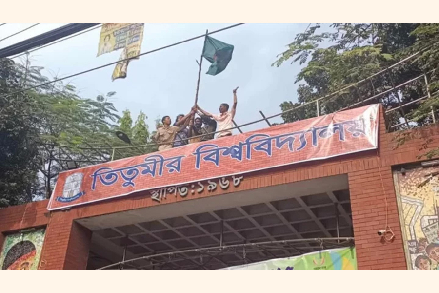Students of Government Titumir College hang a banner at the main gate of the college declaring it as a university —photo collected