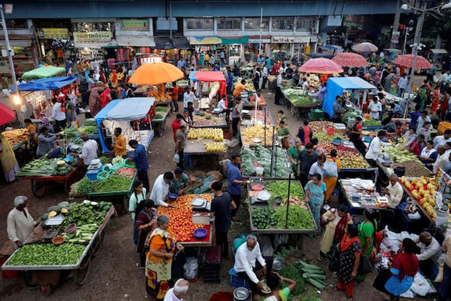 Customers buy fruits and vegetables at an open air evening market in Ahmedabad, India, August 21, 2023.