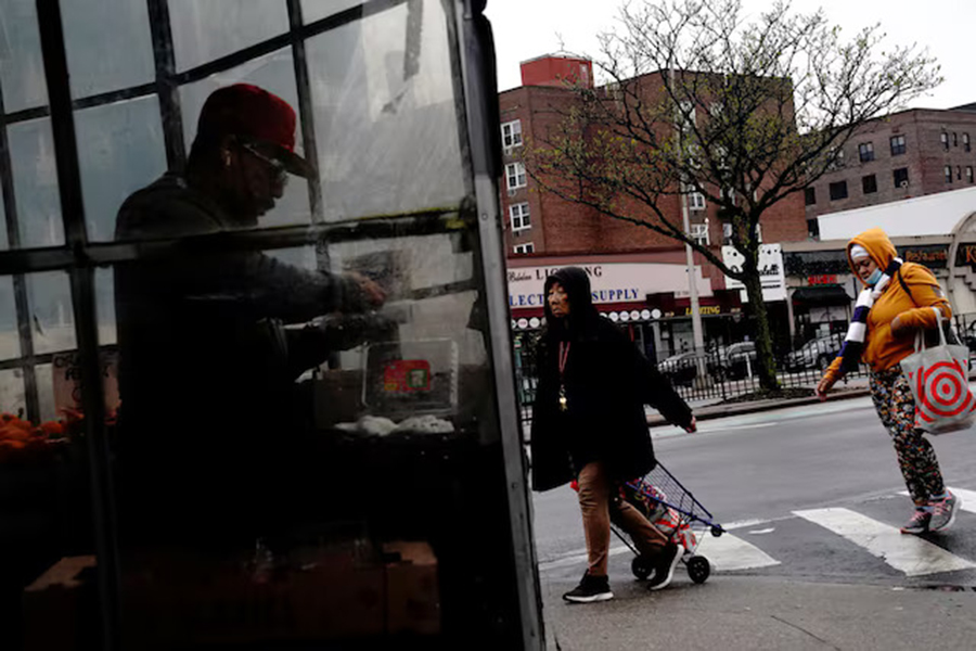 Pedestrians cross the street as a man sorts berries inside a grocery store in Forest Hills, a neighbourhood in the Queens borough of New York City, US on May 2, 2022 — Reuters/Files