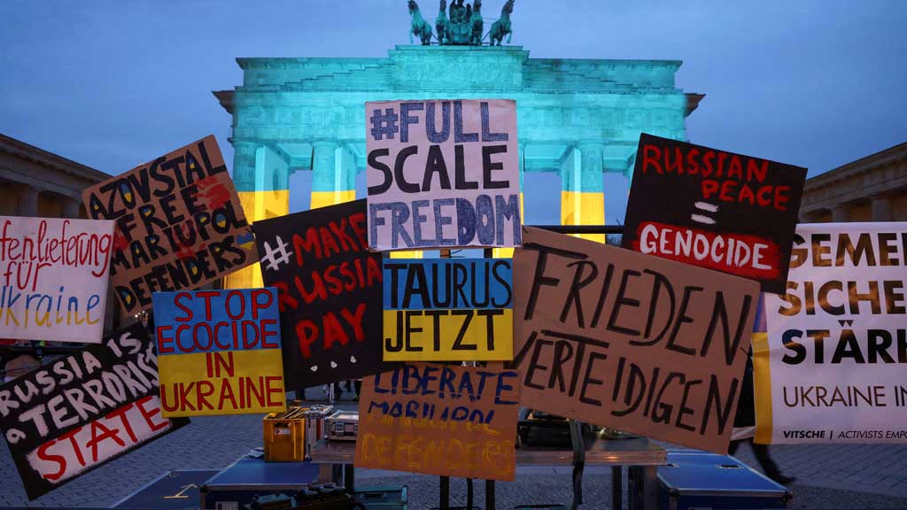 Placards are pictured as the Brandenburg Gate in Berlin is illuminated with the colors of the Ukrainian flag to mark the third anniversary of Russia's invasion of Ukraine, in Berlin, Germany, February 24, 2025. REUTERS
