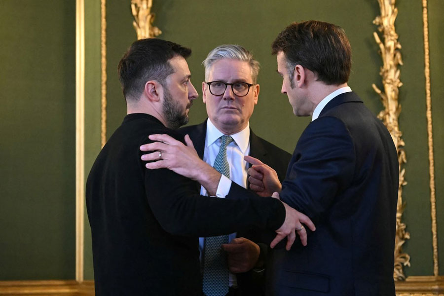 Ukraine's President Volodymyr Zelenskiy, Britain's Prime Minister Keir Starmer and France's President Emmanuel Macron embrace after holding a meeting during a summit at Lancaster House in central London, Britain March 2, 2025.