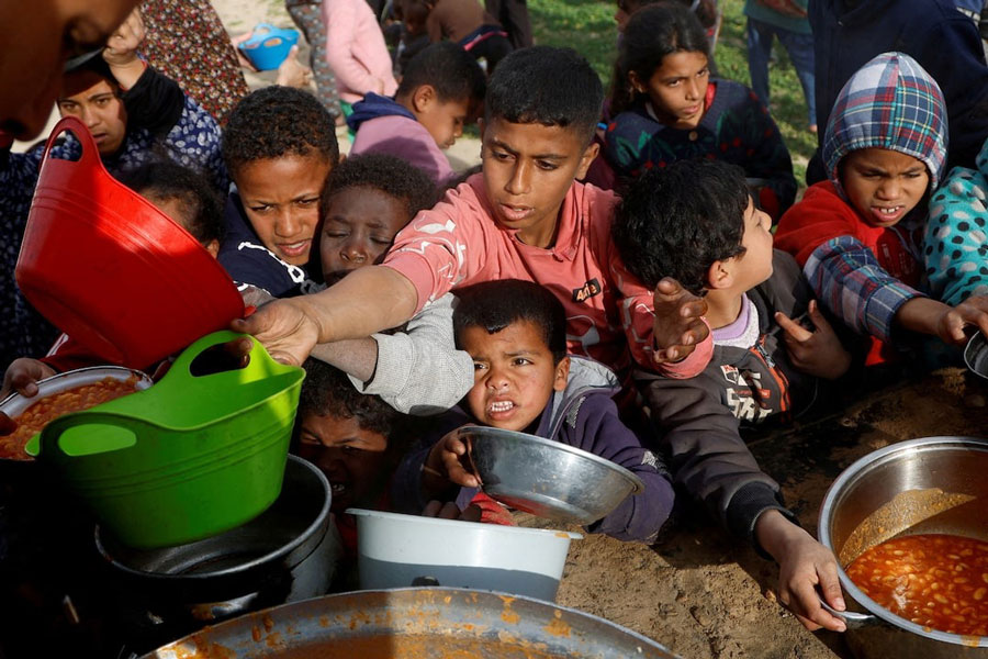 Palestinian children gather to receive food cooked by a charity kitchen, during the Muslim holy month of Ramadan, in Khan Younis, in the southern Gaza Strip, March 3, 2025.