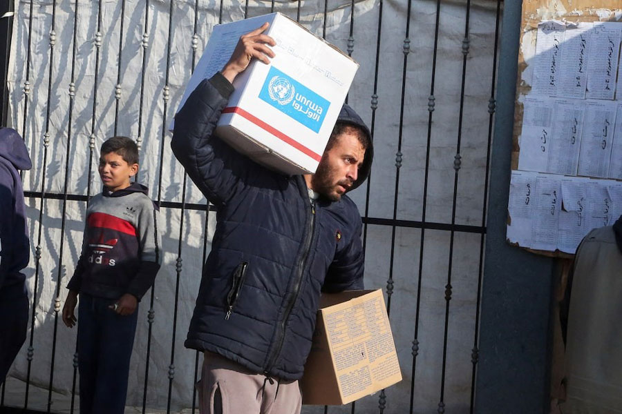 A Palestinian man carries aid boxes provided by UNRWA outside a distribution point, amid a ceasefire between Israel and Hamas, in Khan Younis in the southern Gaza Strip, February 4, 2025.