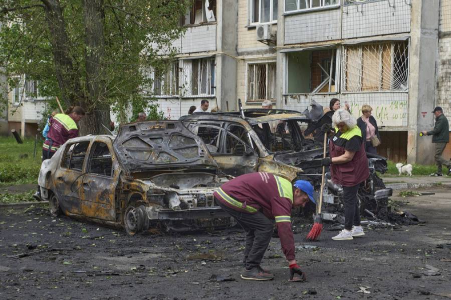 Municipal workers clean up around burnt cars in the residential area following Russia’s drone attack in Kyiv, Ukraine, Sunday, May 4, 2025.