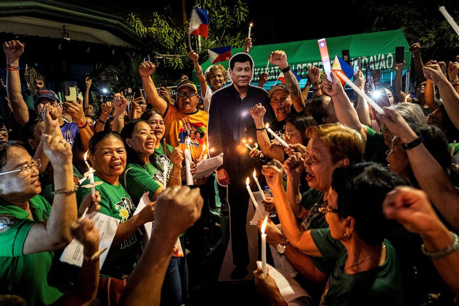 Supporters of the arrested former Philippine President Rodrigo Duterte hold candles while singing Happy Birthday during a celebration outside his residence to mark his birthday, in Davao City, Philippines, March 28, 2025.