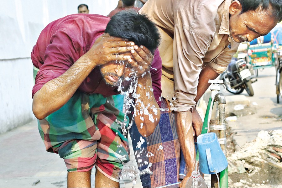 Amid sweltering heat, a man is seen cooling himself by washing his face with water from a roadside tap at R.K. Mission Road in Dhaka on Friday. — FE photo by Shafiqul Alam