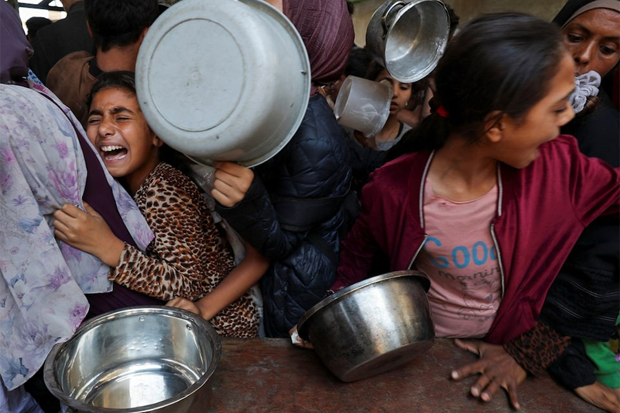 Palestinians wait to receive food cooked by a charity kitchen, in Gaza City on May 21 — Reuters photo