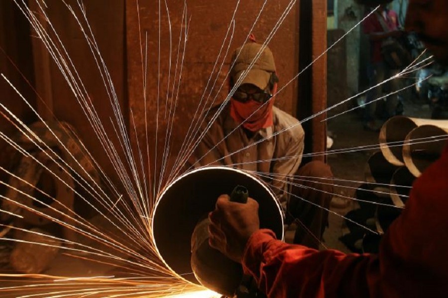 A worker cuts metal inside a workshop manufacturing pipes in Mumbai, India August 11, 2017. Reuters