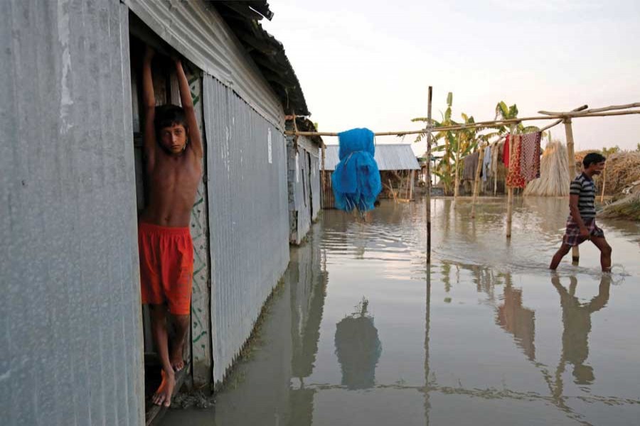 A boy stands in the door of his flooded house in Bogra, Bangladesh, August 20, 2017. —Reuters photo