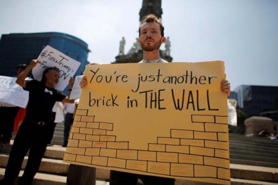 A demonstrator holds a placard during a protest against Donald Trump's visit to Mexico at the Angel of Independence monument in Mexico City on August 31, 2016. — Photo: Reuters