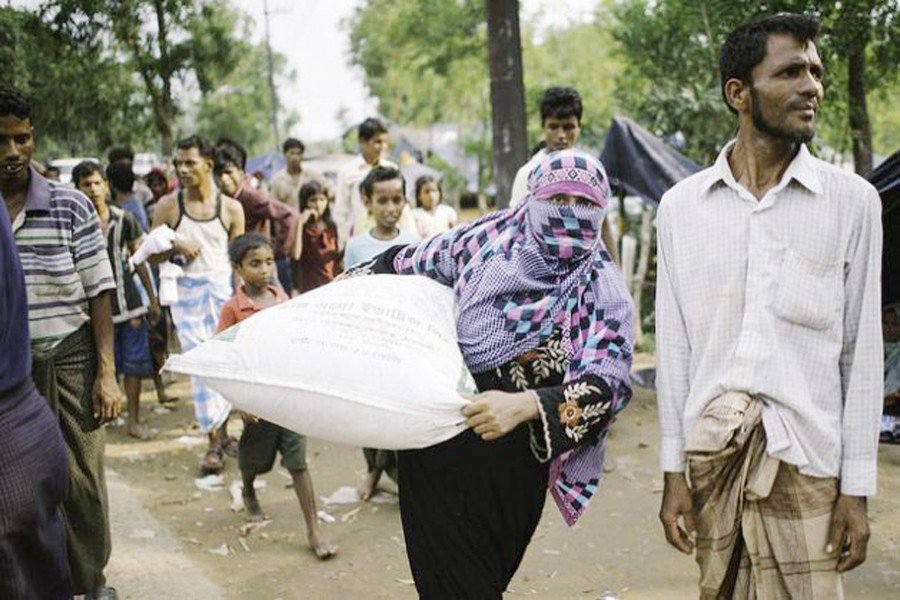 A Rohingya refugee woman carrying relief supplies to her makeshift shelter — Umer Aiman Khan/IPS
