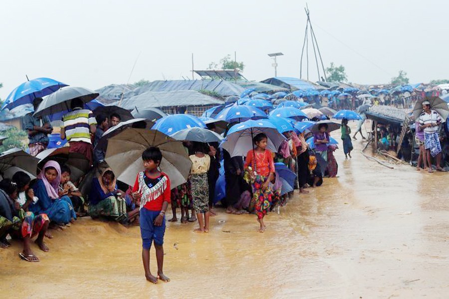 Rohingya refugees queue in the rain to receive food at Kotupalang refugee camp near Cox's Bazar recently — Reuters