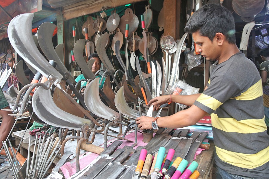 A customer buying knives at a shop at Karwanbazar in the city — FE Photo