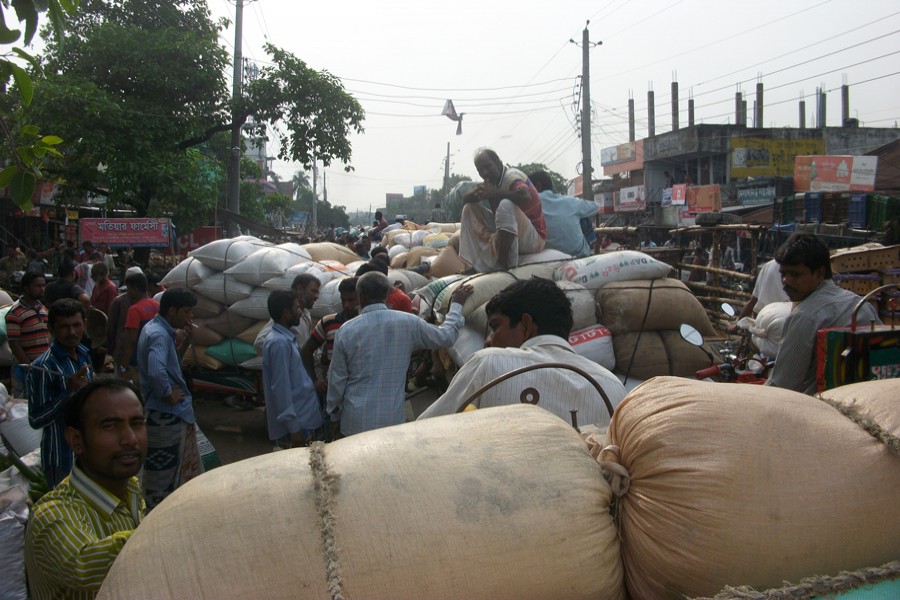 Traders at the Dakbangla Market unloading their goods occupying the Jhenidah-Chuadanga Highway in Jhenidah Sadar on Thursday — FE Photo