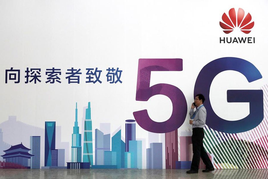 A man talks on his phone beside a Huawei billboard featuring 5G technology. —Photo: Reuters