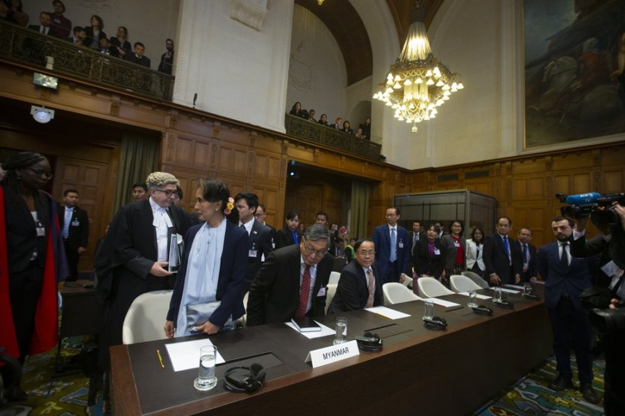 Myanmar's leader Aung San Suu Kyi, with blue scarf and purse, enters the court room prior to addressing judges of the International Court of Justice for the second day of three days of hearings in The Hague, Netherlands, Wednesday, Dec. 11, 2019. (AP Photo/Peter Dejong)