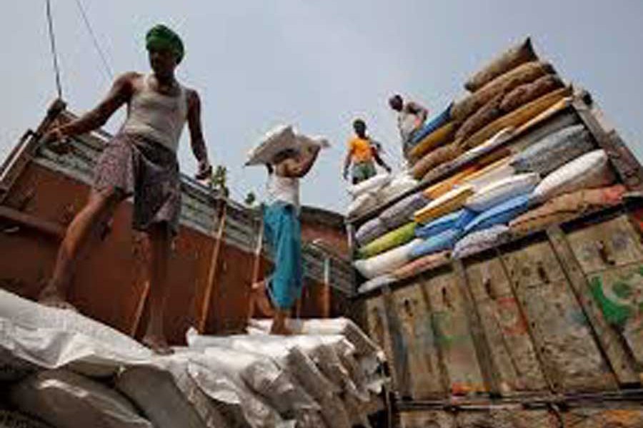 A labourer carries a sack filled with sugar to load it onto a supply truck at a wholesale market in Kolkata, India — Reuters