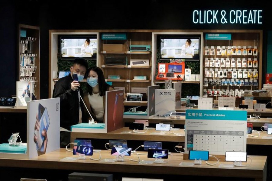 People wearing protective masks look at phones at an electronic retailer in Beijing, China on March 25, 2020 — Reuters photo