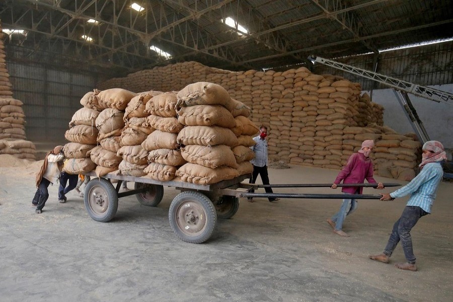Labourers move a cart loaded with rice bags inside a food processing unit, which was reopened after weeks-long shutdown to slow the spread of coronavirus disease (COVID-19), on the outskirts of Ahmedabad, India, April 20, 2020. — Reuters/Files