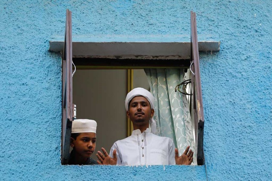 Muslim boys look out from the window of their house during Eid al-Fitr, the Muslim festival marking the end of the holy fasting month of Ramadan, amid the spread of the coronavirus disease (Covid-19), in the old quarters of Delhi, India, May 25, 2020. REUTERS