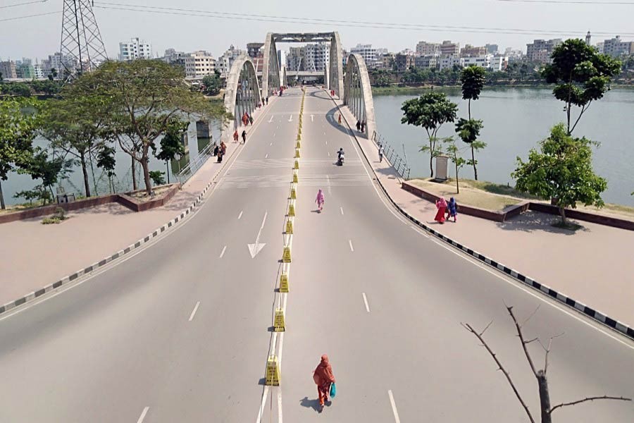 Pedestrians walking along an almost empty street in Hatirjheel area in Dhaka during a lockdown imposed due to the coronavirus