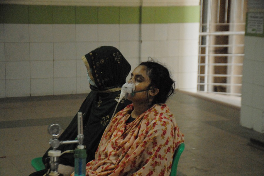 A woman with Covid-19 symptoms, who travelled all the way from Cumilla to Dhaka seeking treatment, waits at Mugda Medical College Hospital with her oxygen mask on
