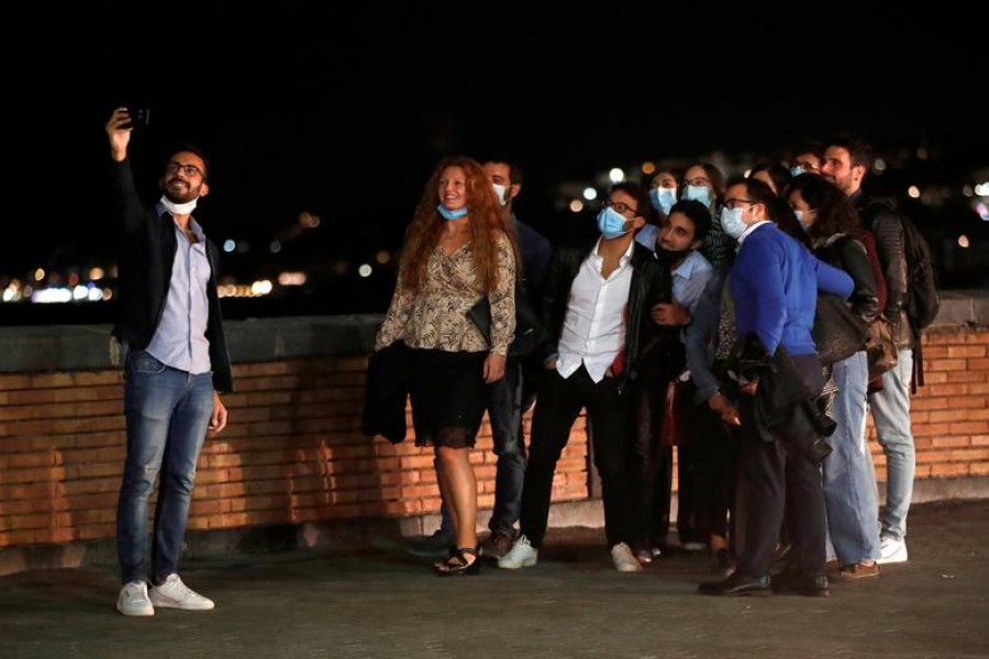 People pose for a selfie in Naples, where masks are required outdoors 24 hours a day and bars and restaurants are required to close at 11.00.p.m. (2100GMT), as part of efforts to contain the coronavirus disease (COVID-19) outbreak, Italy October 6, 2020. REUTERS/Ciro De Luca