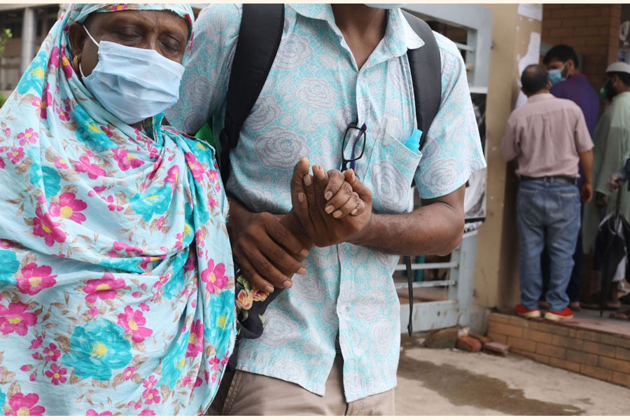 A woman with the support of her son leaving a hospital in Dhaka after giving sample for Covid-19 test - FE Photo