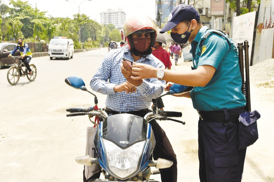 A policeman checks a man's movement pass during a lockdown to curb the spread of Covid-19 in Dhaka on April 14 —Xinhua Photo