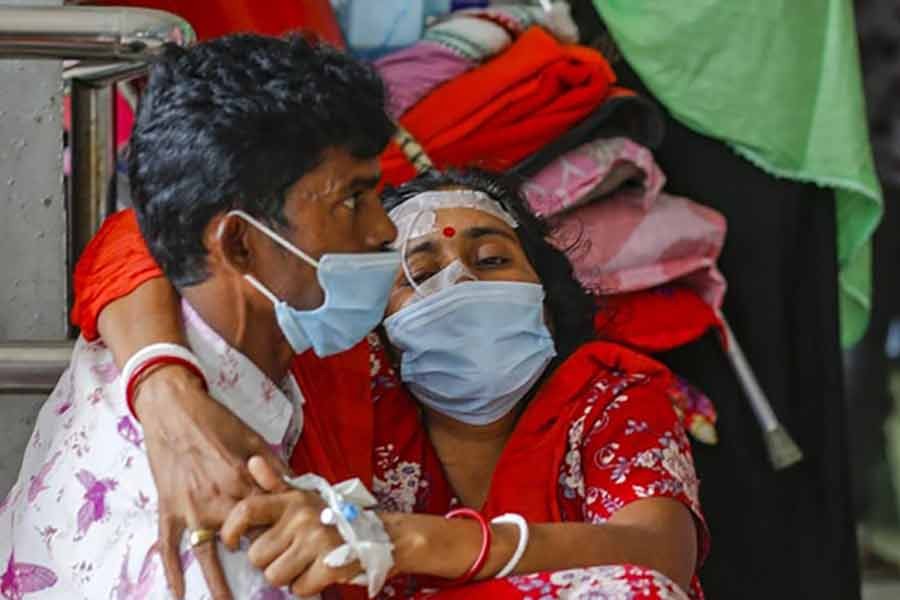 Husband carrying suspected coronavirus patient Shipra, who gave a single name and also has typhoid, into Dhaka Medical College Hospital as they arrive from Bogura recently -bdnews24.com file photo