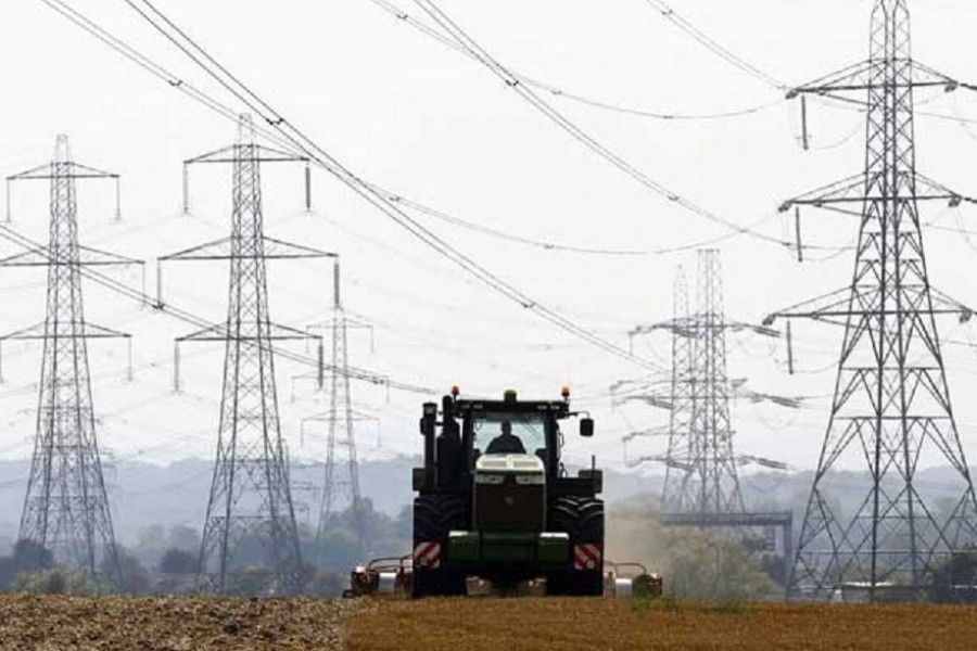 A farmer works in a field surrounded by electricity pylons in Ratcliffe-on-Soar, in central England, Sep 10, 2014. REUTERS/Darren Staples
